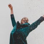 Woman jumping up looking happy with confetti raining down - square