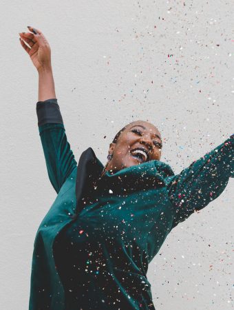 Woman jumping up looking happy with confetti raining down - square